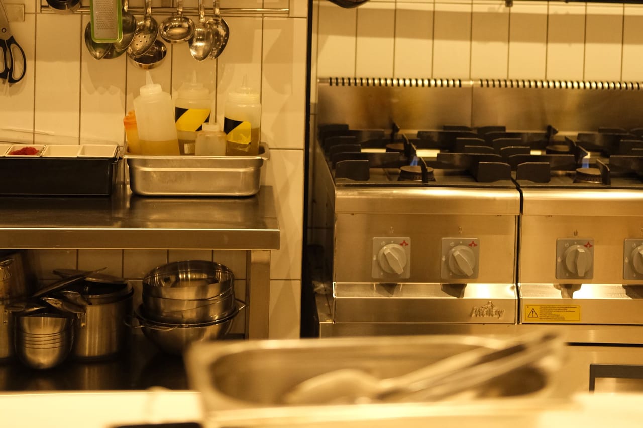 Cozinha industrial bem equipada com panelas suspensas e utensílios