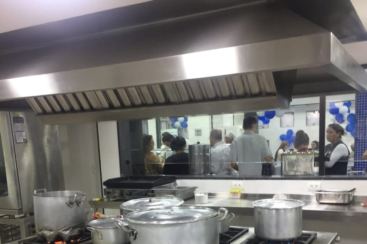 Cozinha industrial em operação com fogões, panelas e bancadas em aço inox