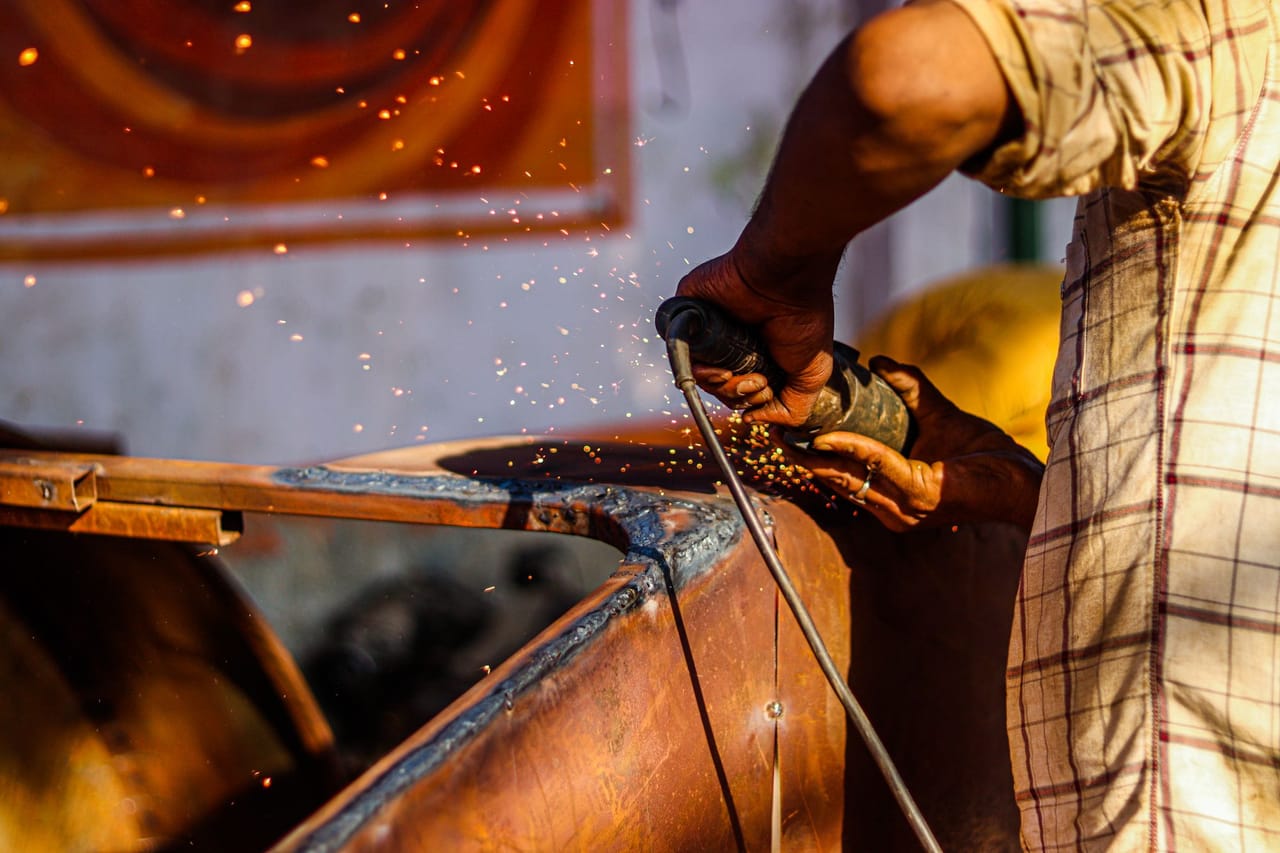 Artesão utilizando esmerilhadeira com faíscas em oficina metalúrgica